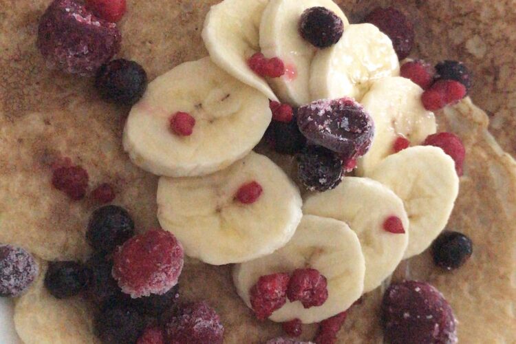 Zeigt die Protein Pancakes serviert mit Beeren und Bananae